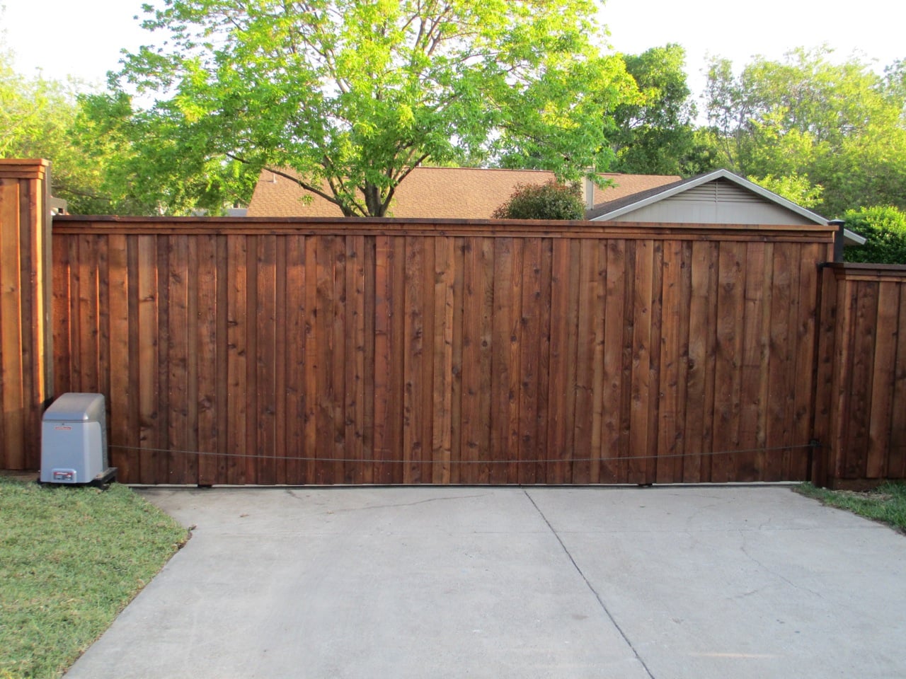 wood gates - wood board on board sliding gate at the entrance of concrete driveway