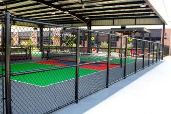 Chain-link fencing enclosing  pickleball courts at Chicken N Pickle