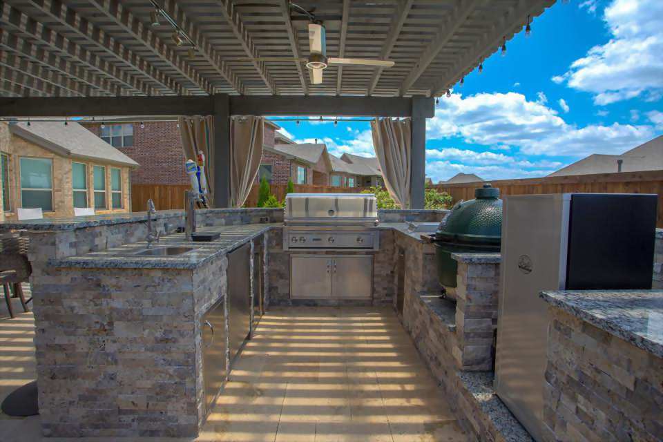 stone outdoor kitchen under pergola by texas best fence and patio
