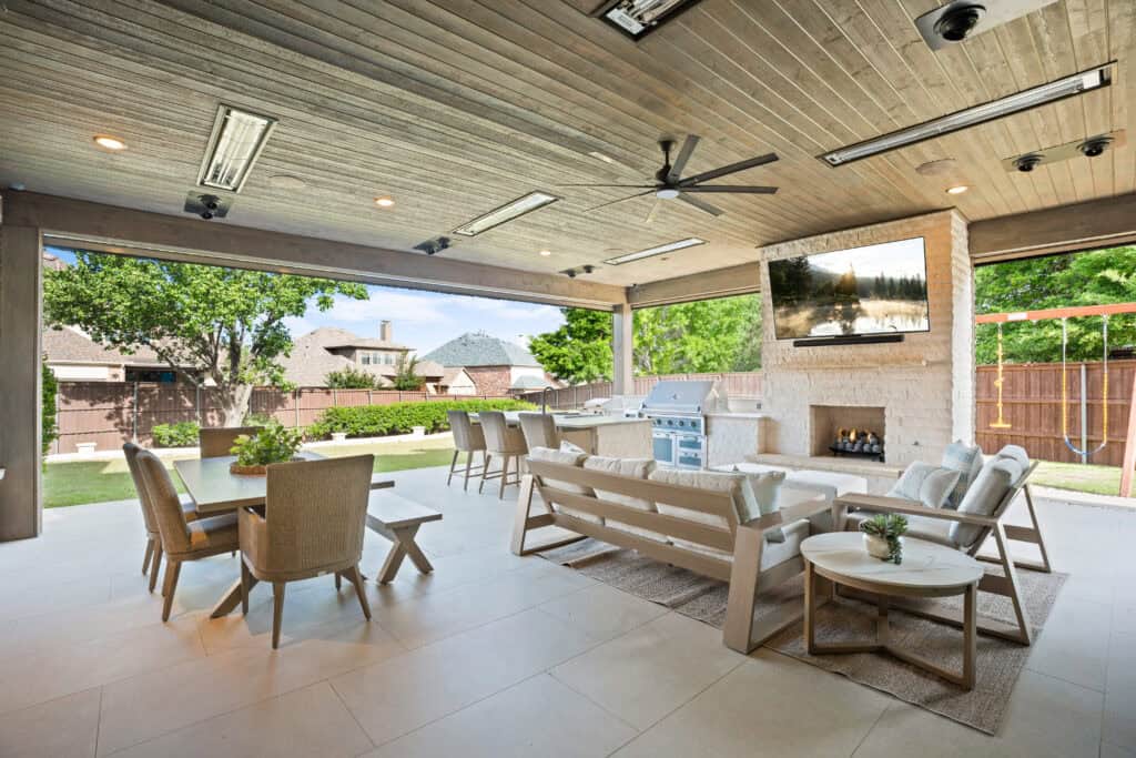 Covered outdoor living area with a fireplace in Castle Hills built by Texas Best Fence & Patio